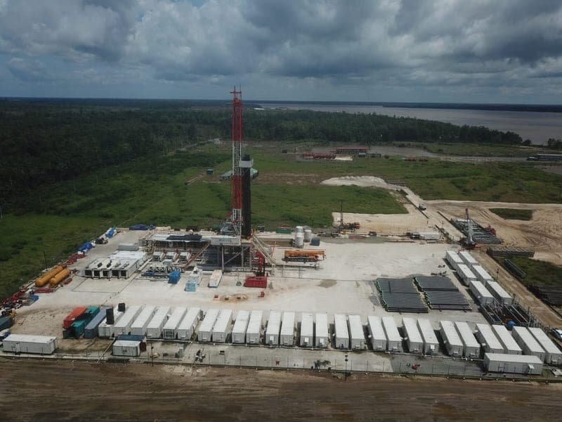 Pipe racks beside water at the Atamba location, with a forklift at work